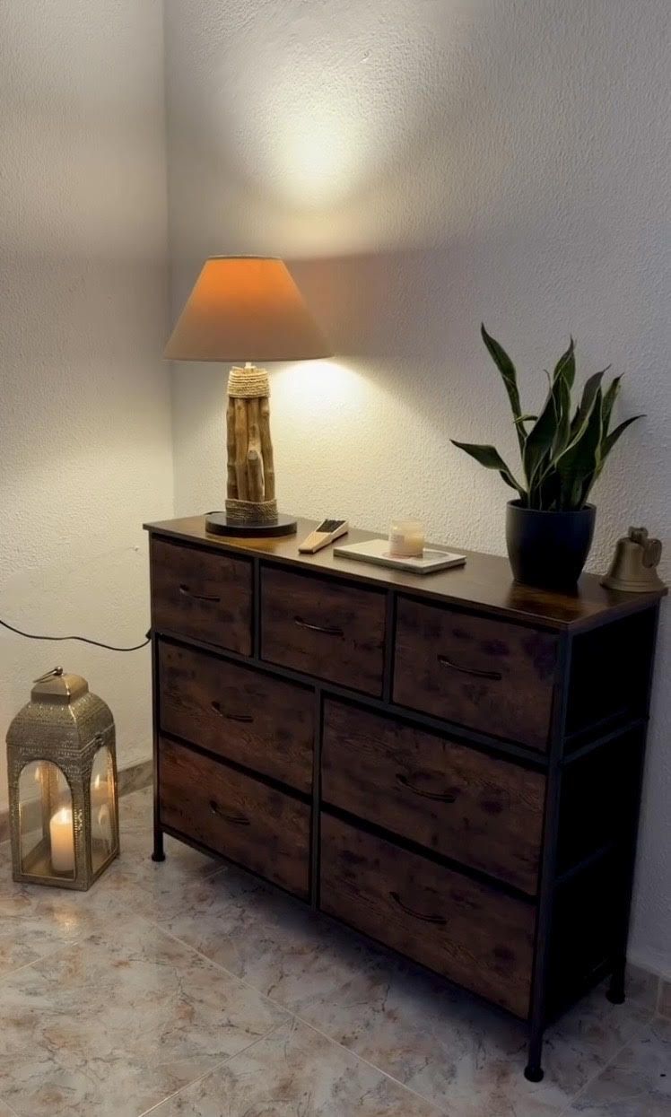 Hyggeligt hjørne med rustik kommode, drivtømmerlampe og tændt lanterne fra Spanien